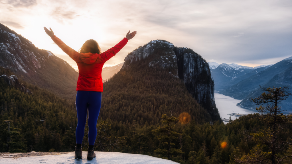 An image of a person celebrating their life fulfillment on a mountain peak.